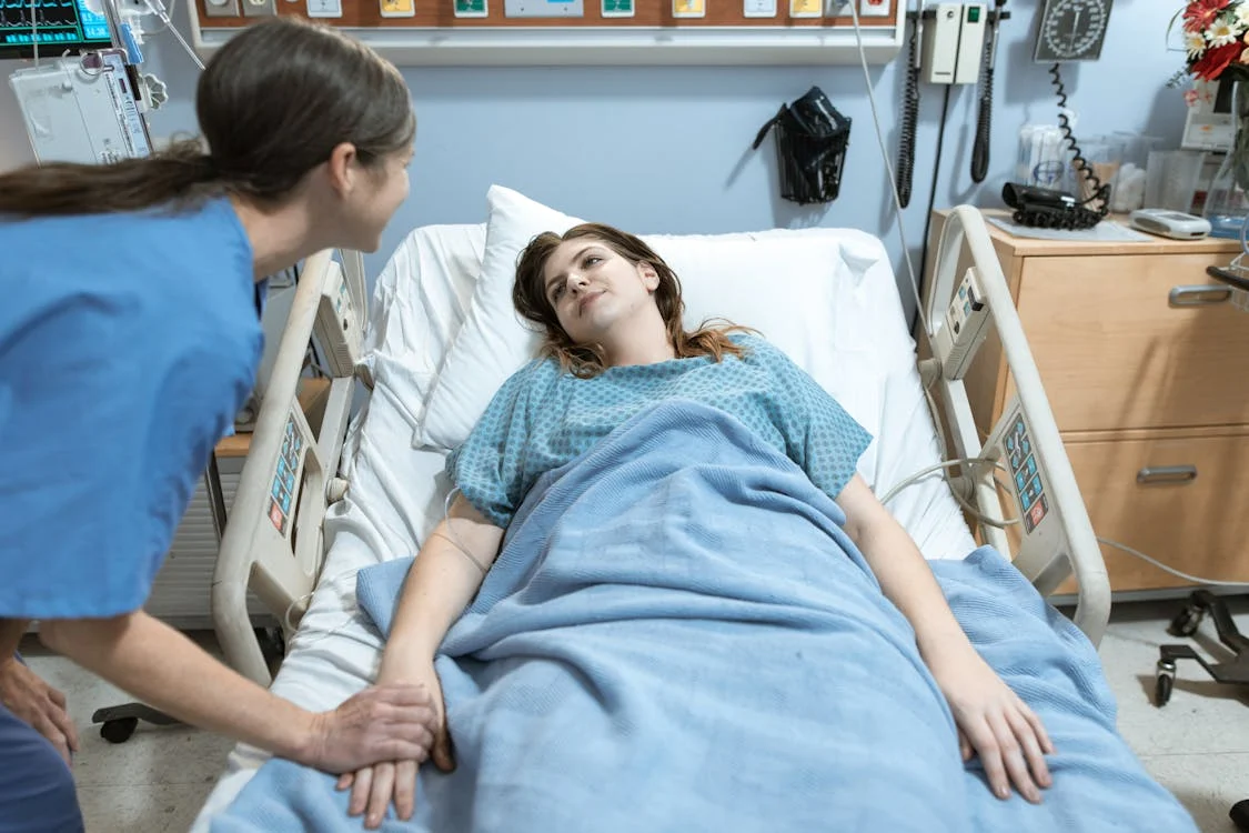 vrouw in blauw shirt liggend op ziekenhuisbed