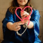 girl in blue jacket holding red and silver Stethoscoop